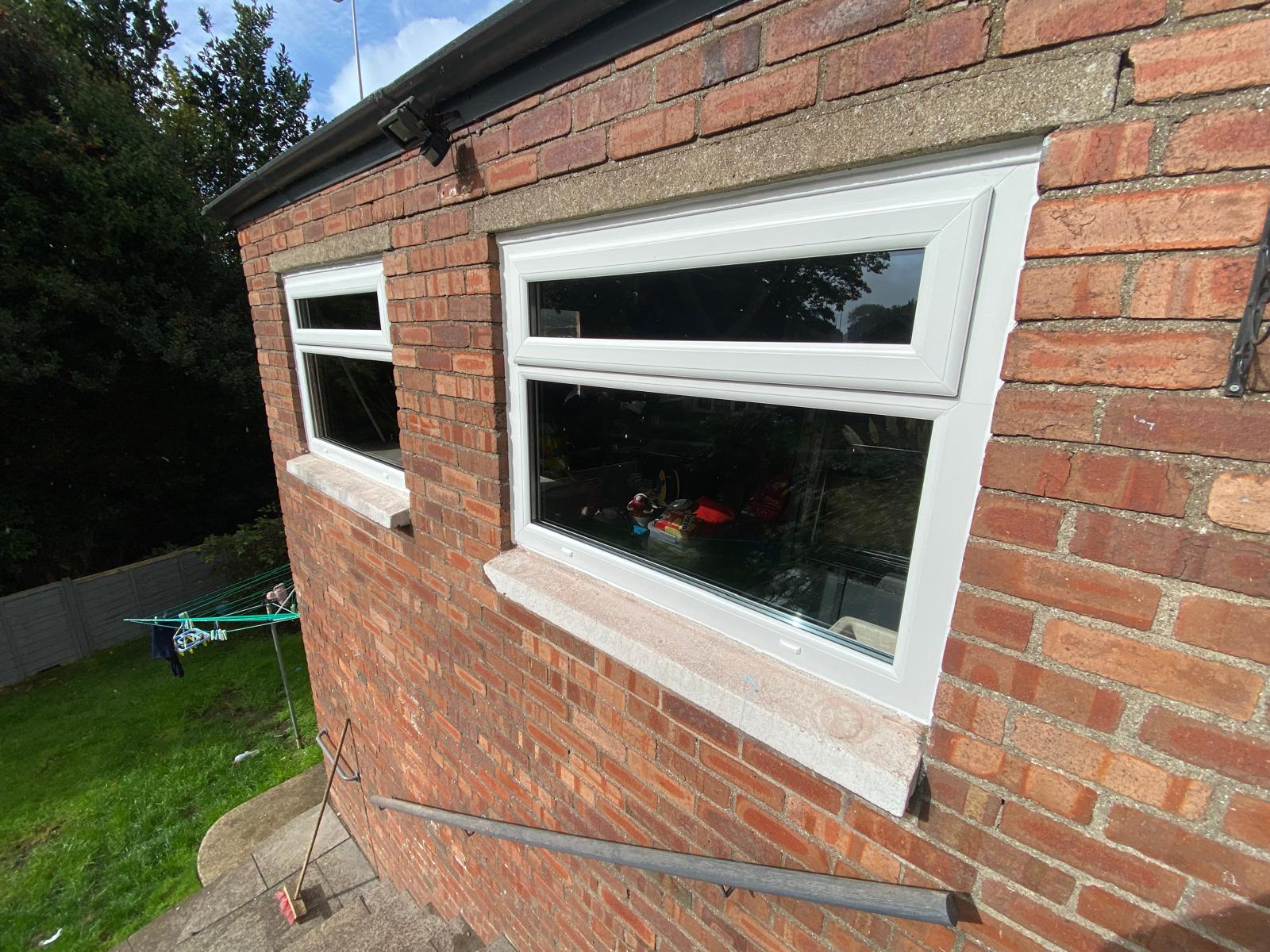 Two white PVCu windows with top-opening vents fitted to a garage wall