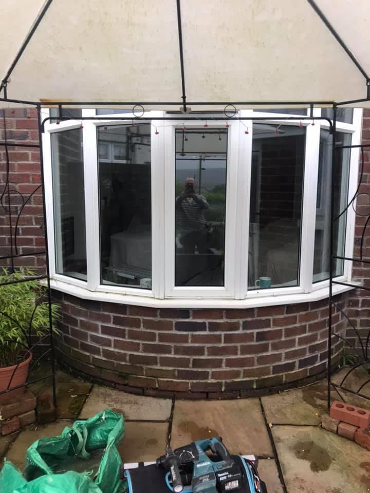 Original white bow window on a brick bay before work began