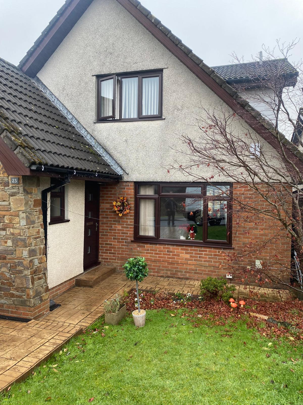 Dark brown windows and matching front door on a detached house
