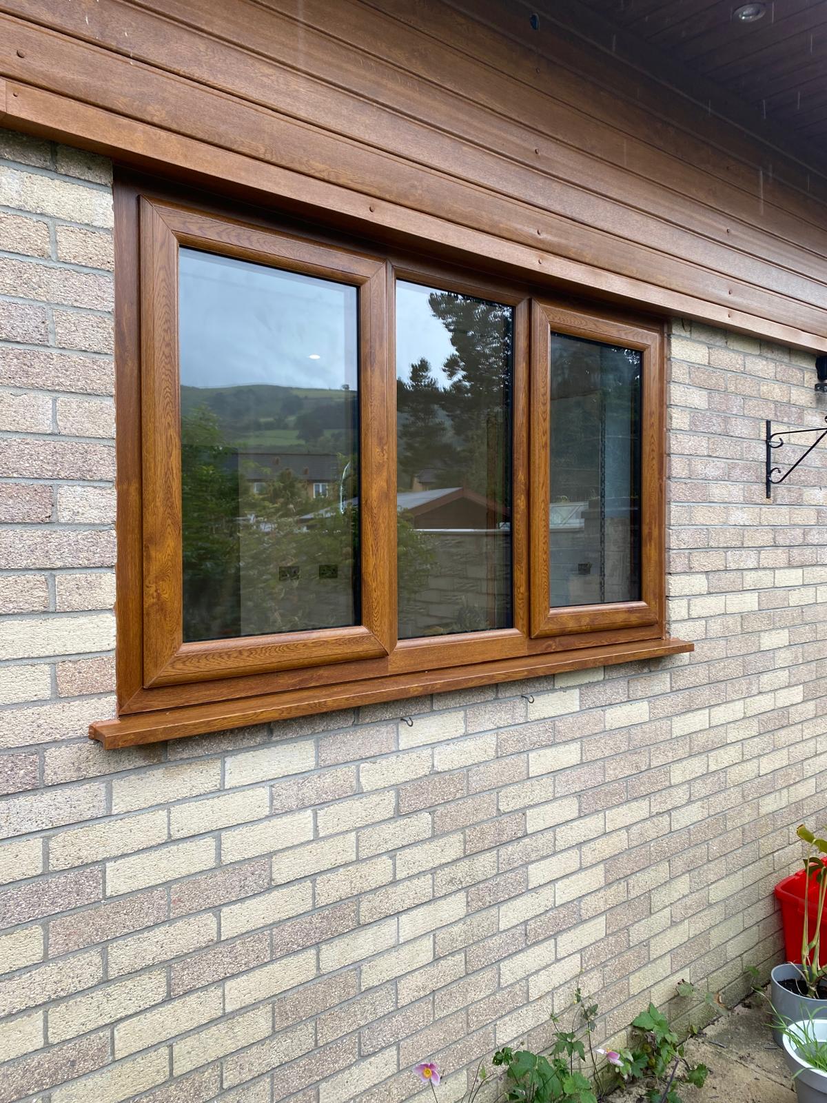Golden oak woodgrain PVCu window with three panes and matching sill