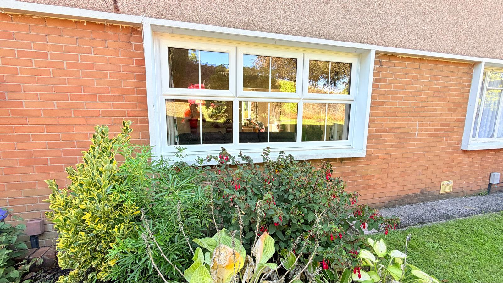 Large white PVCu window with Georgian bars and three top vents set into red brick